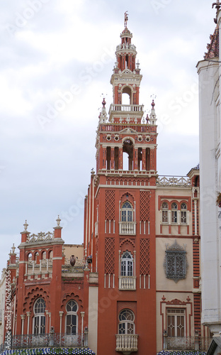 The historic Giralda of Badajoz building with its distinctive red neomudejar architecture and ornate bell tower replica under a cloudy sky in Badajoz, Extremadura, Spain.