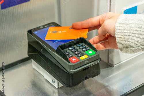 Photos Close-up of a customer making a contactless payment with a credit card at a checkout terminal