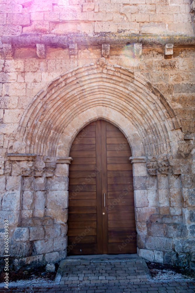 Fototapeta premium Architectural view of the 13th-century Cistercian main portal with pointed archivolts and a wooden door at the Monastery of Santa Maria de Palazuelos in Corcos del Valle, Valladolid, Castilla y Leon