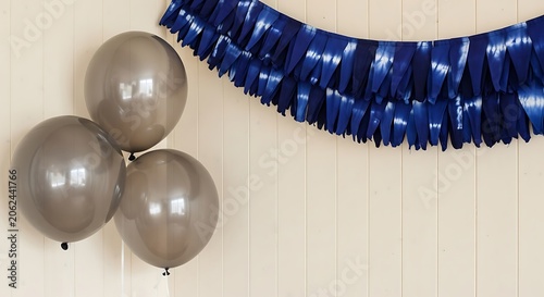 Silver balloons tied together with blue tinsel on cream wall