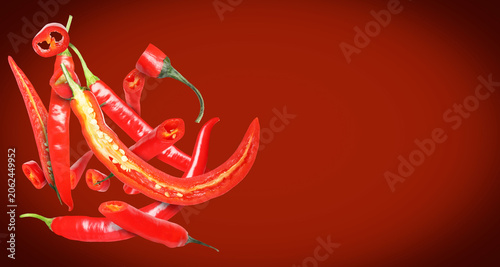 Foto Chili peppers falling against red background