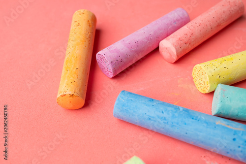 Multicolored chalk sticks viewed from above on pink backdrop. Preschool concept emphasizes early education, playful creativity and visual learning resources for advertising and educational content.