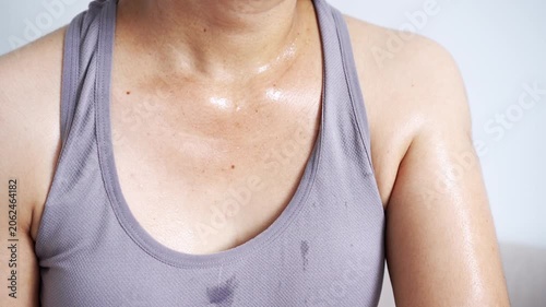 close-up of a sweaty woman in grey athletic wear with sweat drops on her chest and neck after an intense workout, representing fitness dedication, calorie burning, and healthy skin at home