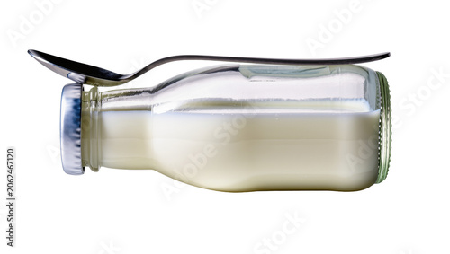 Glass bottle filled with milk and metal spoon on top