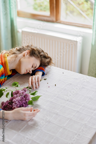 Quadro su tela Woman resting at a table with flowers in a cozy home setting, natural daylight a