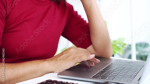 close-up side view of a woman in a red shirt typing on a laptop keyboard at a white desk, focusing on remote work, online learning, digital communication, home office tasks, and business blogging