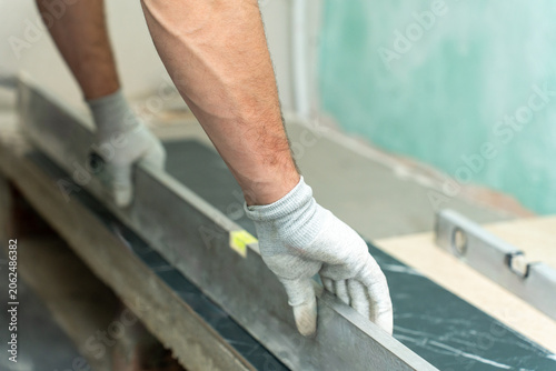 Foto Worker pressing black marble effect tile into place