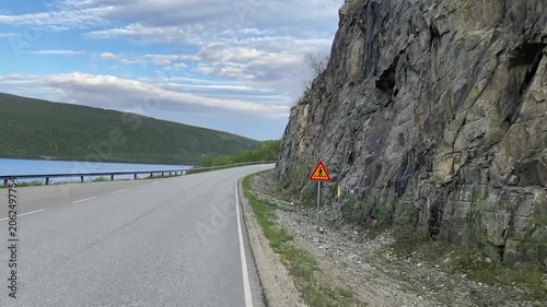 Driving on winding lakeside road through boreal forest in Lapland Finland