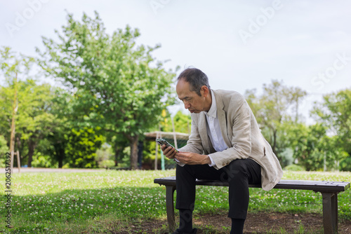 Quadro su tela 公園のベンチでスマートフォンを見る日本人男性