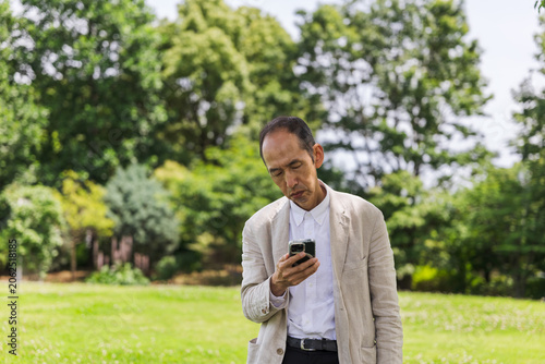 Foto 公園でスマートフォンを見る日本人シニアの男性