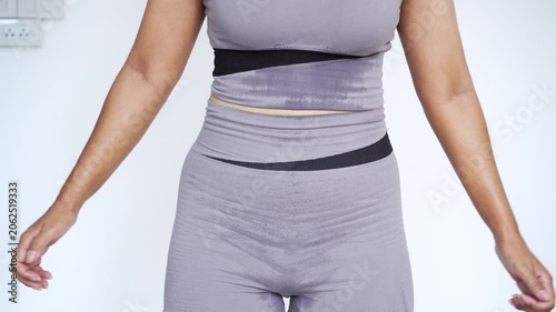 sweaty woman in grey activewear doing a squat exercise at home, focusing on lower body workout, glute training, fat burning, sweat production, weight loss, and fitness motivation