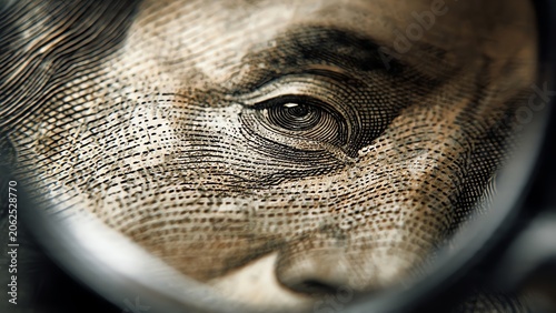 Extreme close-up of Benjamin Franklin's eye on a US hundred-dollar bill, magnified by a lens, symbolizing wealth and financial scrutiny