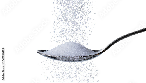 Photos Granulated sugar pouring into metal spoon, white crystals falling