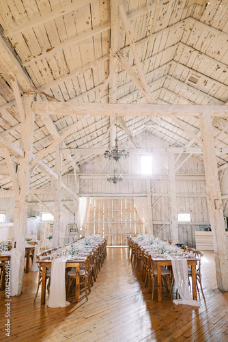 Rustic wedding dinner setup in white wooden barn