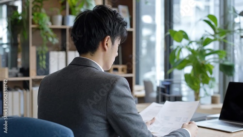 Professional Businessman Reviewing Documents in Modern Office with Natural Light