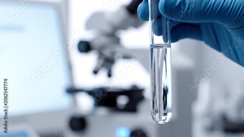 Scientist holding test tube with clear liquid in a laboratory setting