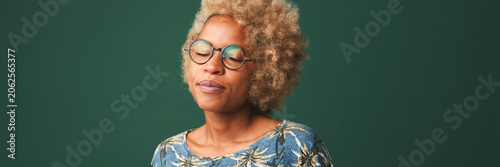 Fotografie Pretty girl in glasses, wearing a blue t-shirt disappointment clapping, isolated on green-blue background, studio shot