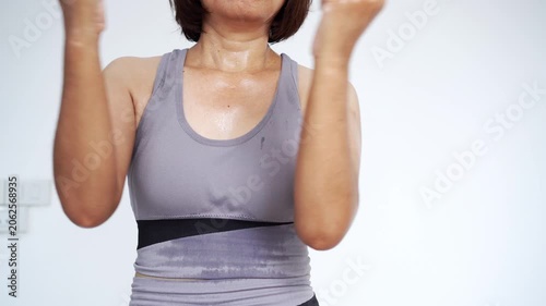 front view of a sweaty woman in grey activewear doing exercise and arm workouts at home, focusing on calorie burning, muscle toning, sweat production, fitness dedication, and a healthy lifestyle