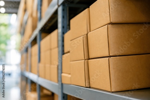 Billede på lærred Cardboard boxes stacked on metal shelves in modern warehouse, organized logistics distribution center, close-up view of package delivery and storage concept