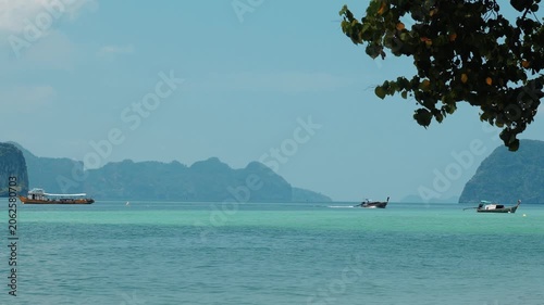 Longtail boats cruising through turquoise water, tropical bay with limestone cliffs and green tree foreground, travel destination background for summer vacation marketing