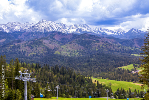 Foto Scenic mountain valley with chairlift and snow covered High Tatras in background