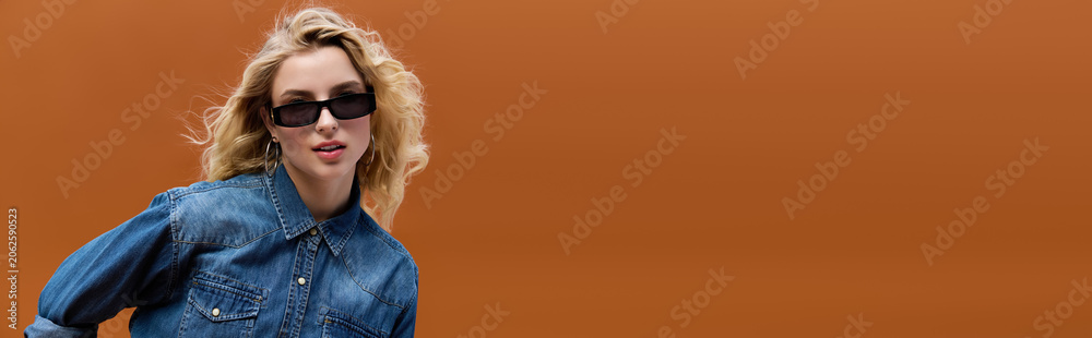 Naklejka premium Confident blonde in trendy denim against a vibrant backdrop