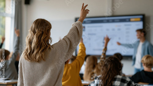 High school classroom buzzes as students raise hands competitively during a gamified quiz session displayed on an interactive smartboard, a teacher moderating with a scoring