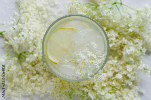 Fotografía Glass with elderberry drink and lemon slices, ice and elderflowers on a light background