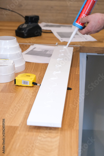 White sealant applied on wooden workbench with plastic strip