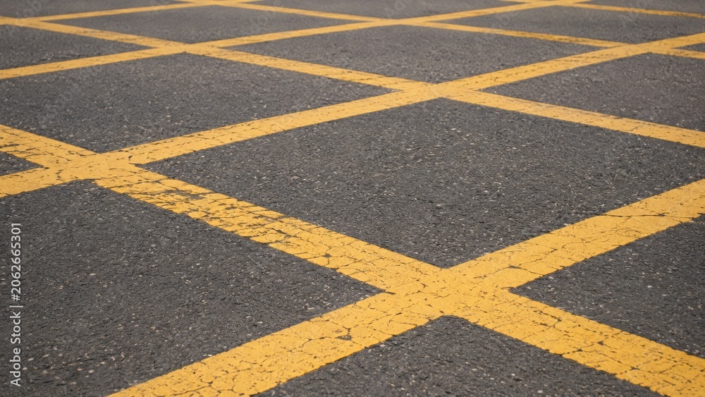 Obraz premium Yellow crosshatch no stopping road markings on dark asphalt.