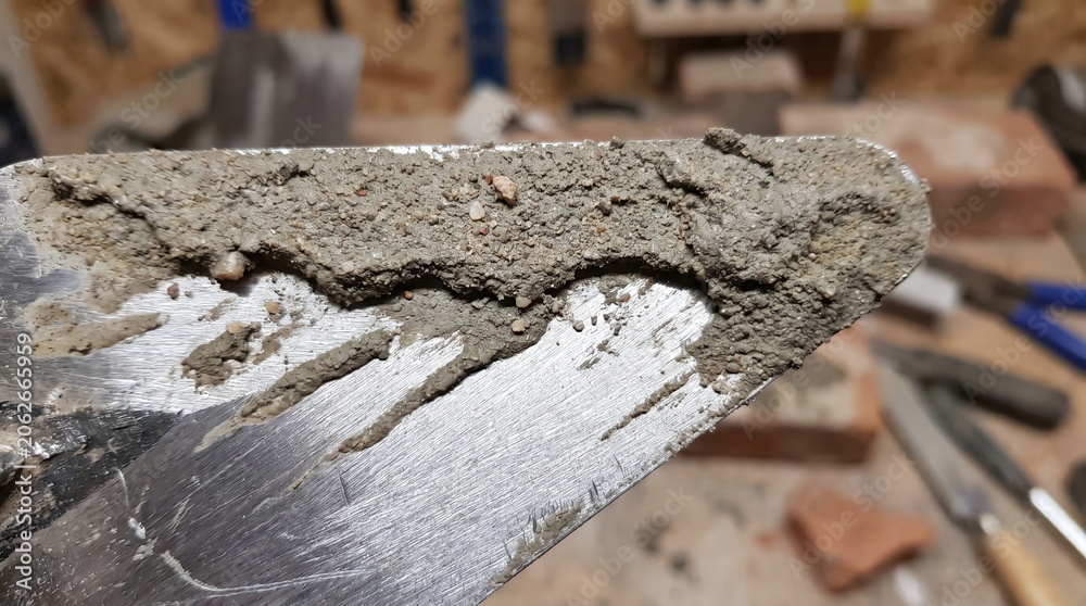 Fototapeta premium Trowel covered with fresh cement mortar for bricklaying work