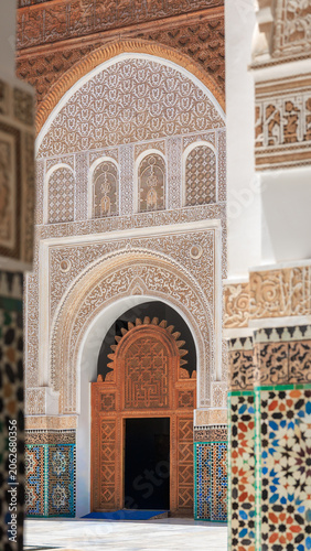 the central pool entrance facade showing complex hand-carved arabesque stucco panels in Ben Youssef Madrasa, Marrakech