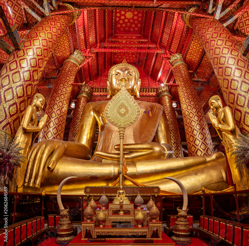 Giant Buddha statue inside the temple of Wat Phanan Choeng, in Ayutthaya Thailand. Surrounded by Beautifully decorated walls and pillars. 
