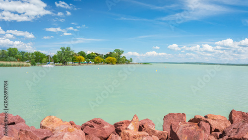 Hungary, Lake Balaton, view of the lake shore with green trees above the water on a sunny summer day.