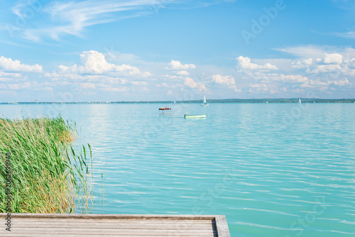 Hungary, Lake Balaton, wooden jetty at the shore with a view of the lake and the other shore on a sunny summer day.