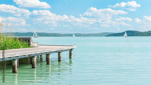 Hungary, Lake Balaton, wooden jetty at the shore with a view of the lake and the other shore on a sunny summer day.