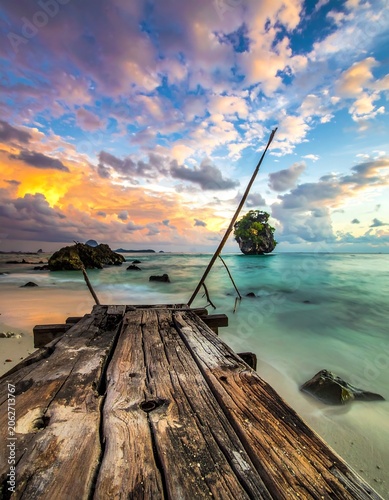 Wooden pier leading to serene ocean isle under vibrant sky