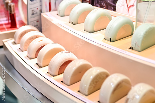 An organized makeup vanity or retail counter displaying various circular cushion foundations in beige