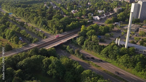 Frankfurt skyline emerging behind residential neighborhood with highway traffic over freeway and suburban houses nestled in lush green trees
