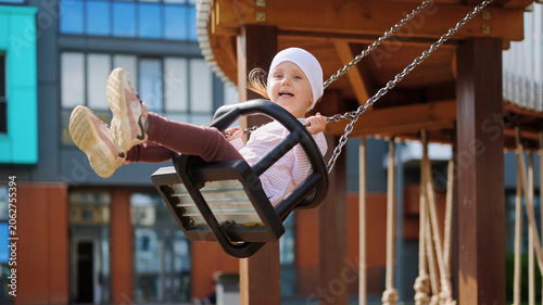Foto Happy little child swinging on a playground with a joyful expression, enjoying outdoor fun in an urban setting
