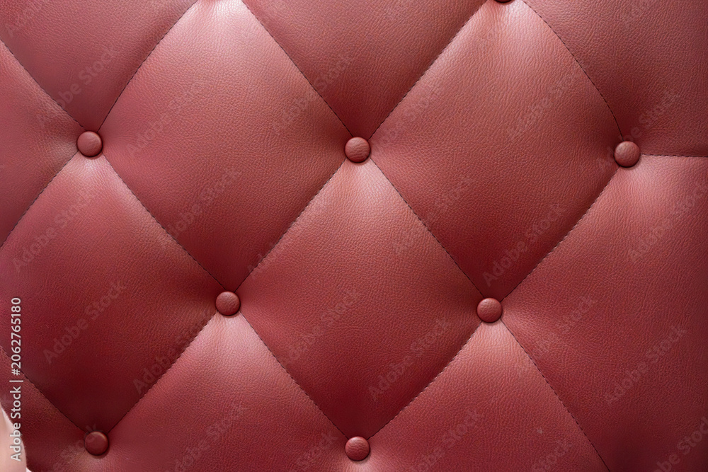 Fototapeta premium Red leather upholstery with quilted pattern showing buttons in a close-up view