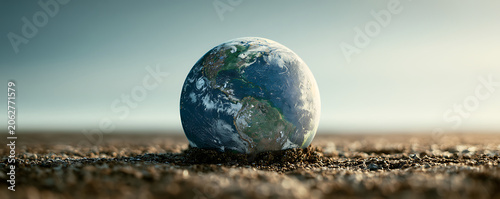 Earth globe resting on parched desert soil under bright sky for climate change concept