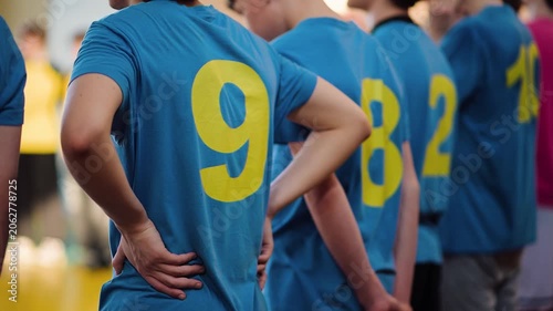 Students line up in blue shirts for sports events at a school gym during a day of competition in the afternoon