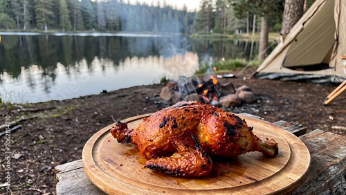 Wooden table with roasted meat and sauce bowl outdoors.