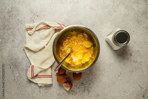 Vista superior de un bol con huevo batido y rodajas de patatas fritas, para la preparación de una tortilla.