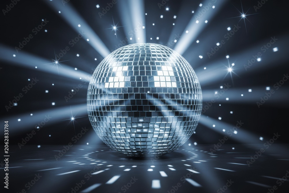 Obraz premium Shining silver disco ball with glowing light rays and sparkles in dark studio