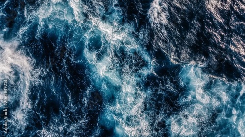 Deep blue ocean water with white foam and turbulent waves seen from above