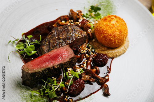 Luxury steak dinner with crispy croquette and berry reduction