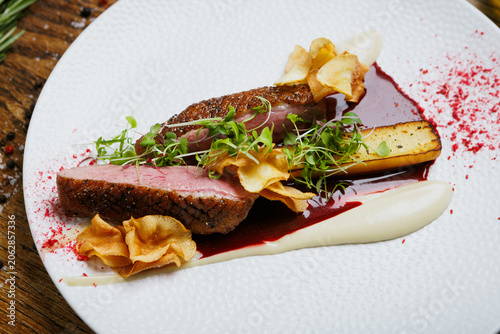 Gourmet duck meat with crispy vegetable chips and herbs