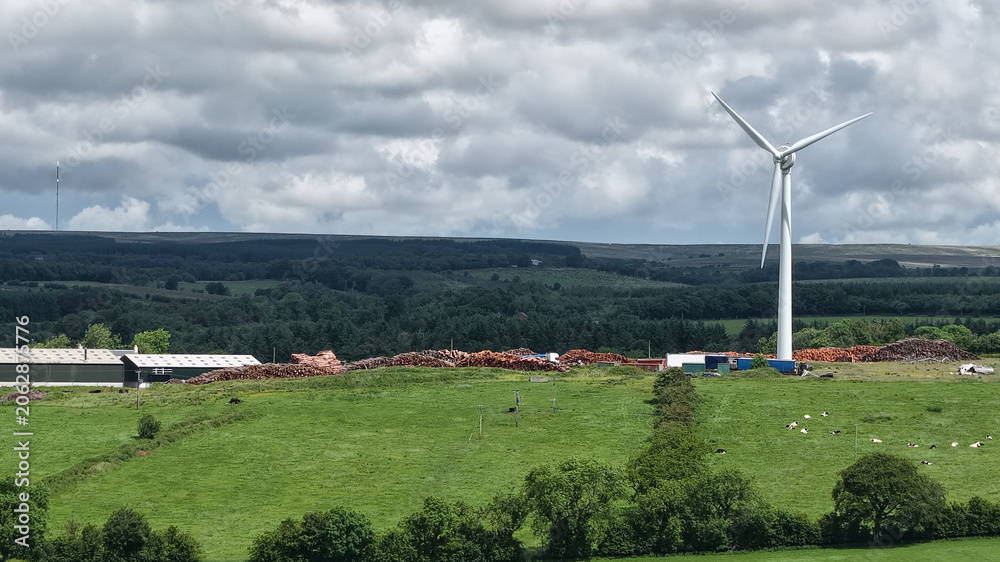 Fototapeta premium Wind turbine generating clean energy on rural farm landscape.